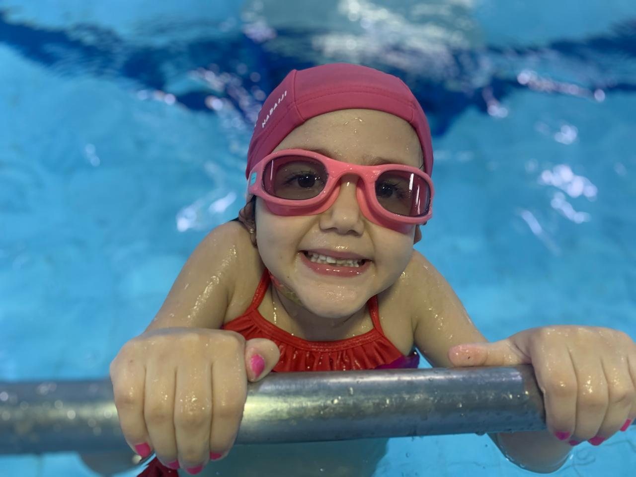 Aluna criança apoiada na borda da piscina aquecida